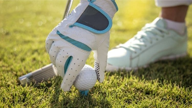 Hand in a Golf Glove Placing Golf Ball on Tee