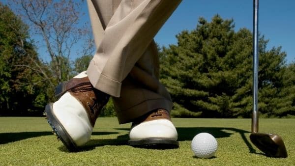 Man standing on golf course with iron and golf ball