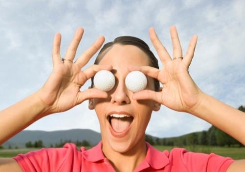 Woman holding golf balls over eyes