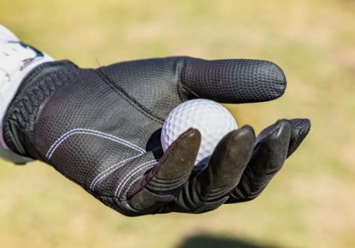 black glove holding golf ball