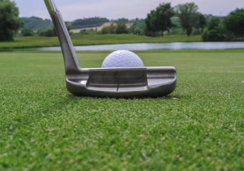 golf putter and ball on grass