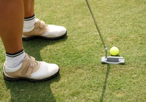 lady golfer hitting ball with putter