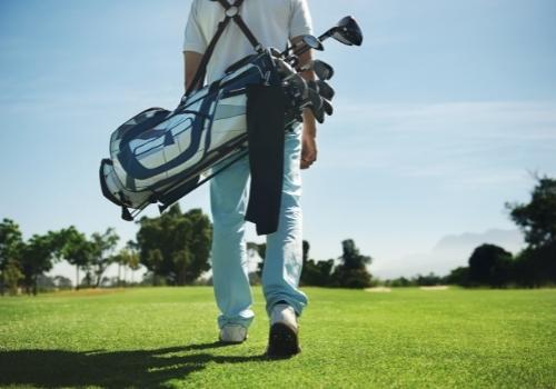 man carrying golf bag